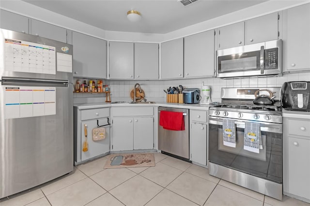 kitchen with decorative backsplash, light tile patterned floors, stainless steel appliances, and sink