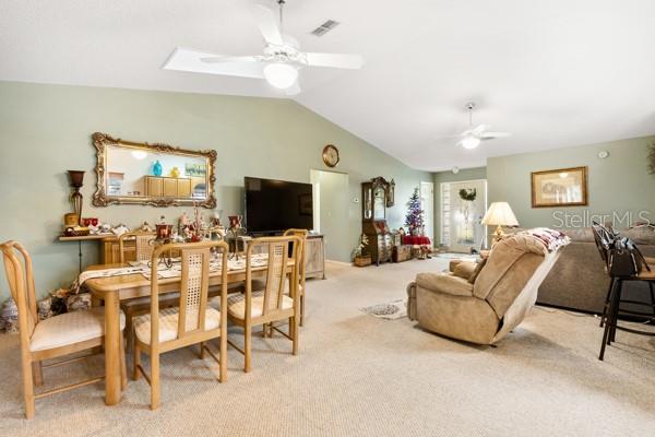 carpeted dining space featuring ceiling fan and lofted ceiling with skylight