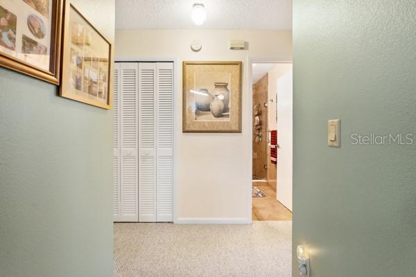 corridor featuring light carpet and a textured ceiling