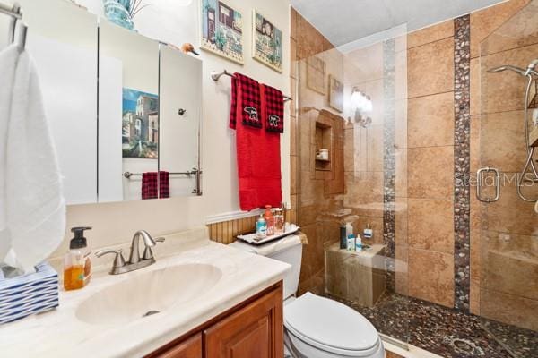 bathroom with a shower with shower door, toilet, and vanity