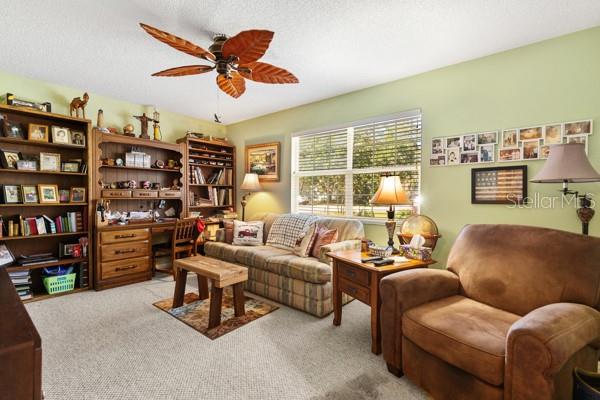 sitting room featuring light carpet, ceiling fan, and a textured ceiling