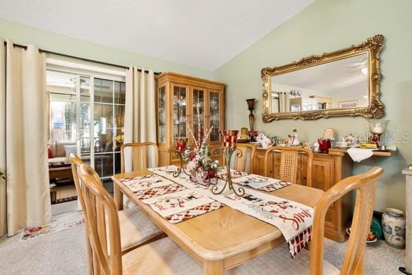 dining room with light carpet, vaulted ceiling, and french doors