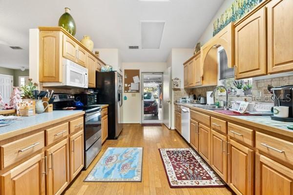 kitchen with backsplash, sink, light wood-type flooring, stainless steel appliances, and light brown cabinetry