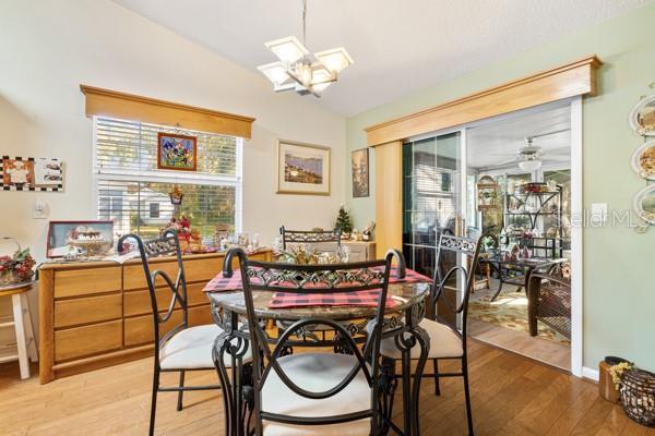 dining space with ceiling fan, light hardwood / wood-style flooring, and vaulted ceiling