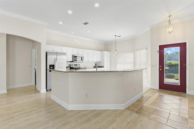 kitchen with hanging light fixtures, ornamental molding, an island with sink, white cabinetry, and stainless steel appliances