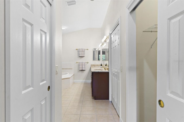 bathroom with tile patterned flooring, vanity, and tiled bath