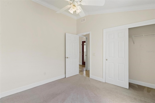 unfurnished bedroom featuring lofted ceiling, crown molding, ceiling fan, light colored carpet, and a closet