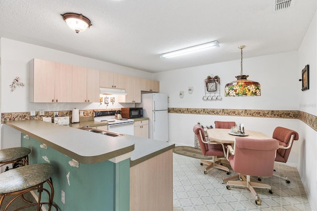 kitchen with kitchen peninsula, white appliances, a textured ceiling, light brown cabinets, and decorative light fixtures