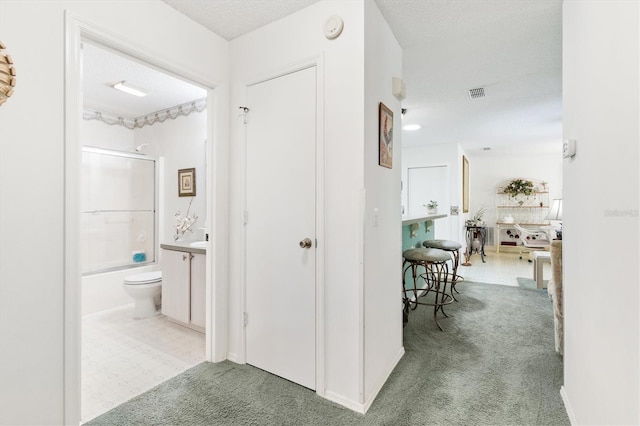 corridor with a textured ceiling and light colored carpet