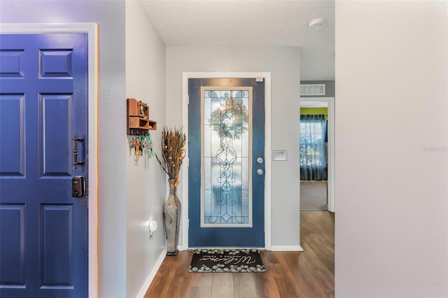 foyer entrance with a textured ceiling and dark hardwood / wood-style floors