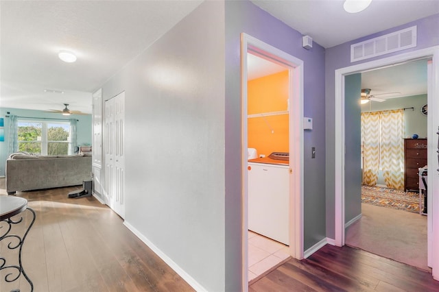 corridor with hardwood / wood-style flooring and washing machine and dryer