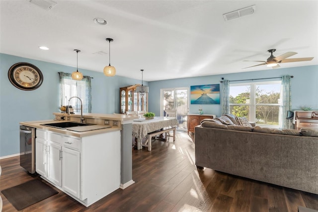 kitchen with sink, hanging light fixtures, dark hardwood / wood-style flooring, a kitchen island with sink, and white cabinets