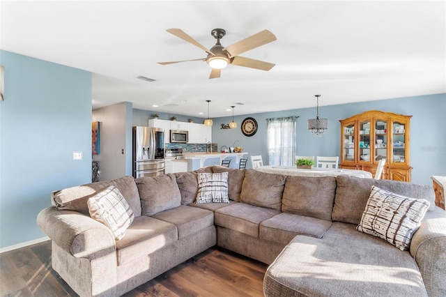 living room featuring ceiling fan with notable chandelier and dark hardwood / wood-style flooring