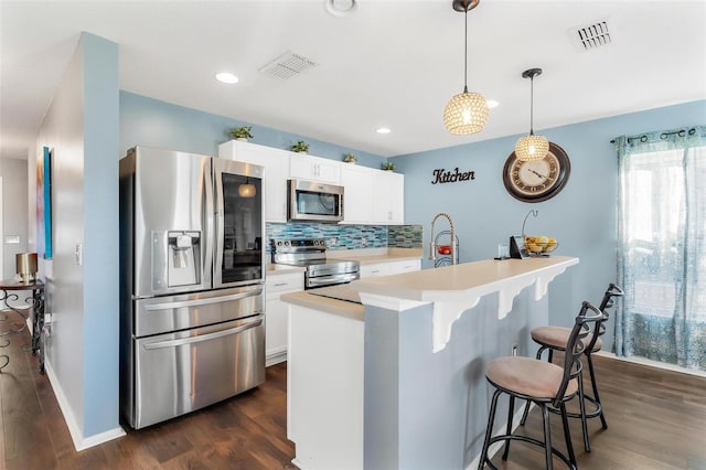 kitchen featuring decorative light fixtures, dark hardwood / wood-style flooring, white cabinetry, and stainless steel appliances