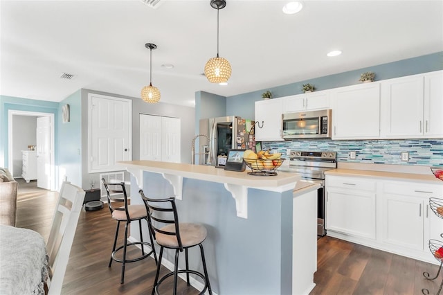 kitchen with dark hardwood / wood-style flooring, stainless steel appliances, white cabinetry, and hanging light fixtures