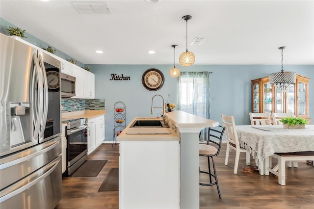 kitchen with appliances with stainless steel finishes, a center island with sink, hanging light fixtures, and sink