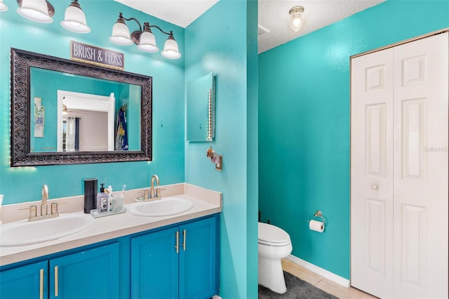 bathroom with toilet, vanity, a textured ceiling, and tile patterned floors