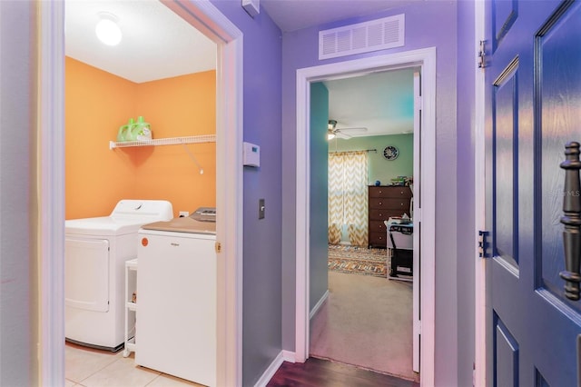 clothes washing area with light colored carpet, washer and clothes dryer, and ceiling fan