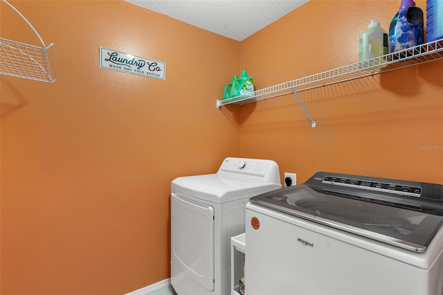 clothes washing area with washer and dryer and a textured ceiling