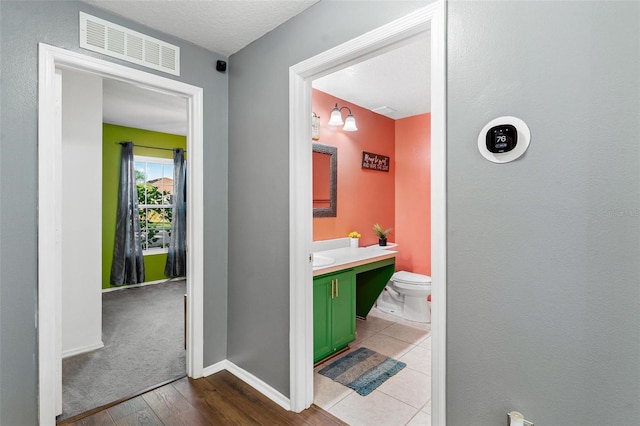 bathroom with vanity, wood-type flooring, a textured ceiling, and toilet