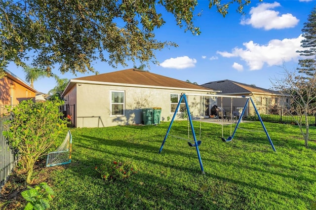 rear view of property with a yard and a playground