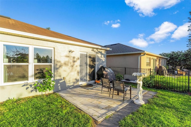 back of property with a lawn and a patio