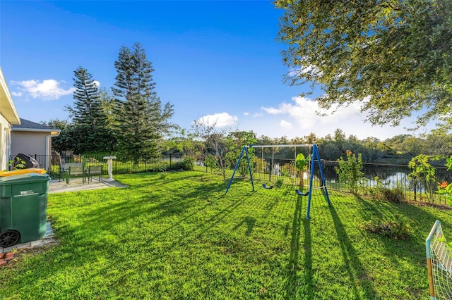 view of yard featuring a playground, a patio area, and a water view