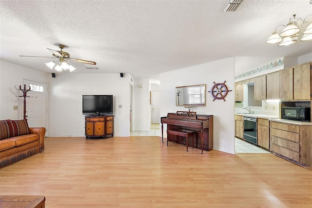 living room featuring ceiling fan with notable chandelier, a textured ceiling, and light hardwood / wood-style floors