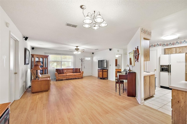 living room featuring ceiling fan with notable chandelier, light wood-type flooring, and a textured ceiling