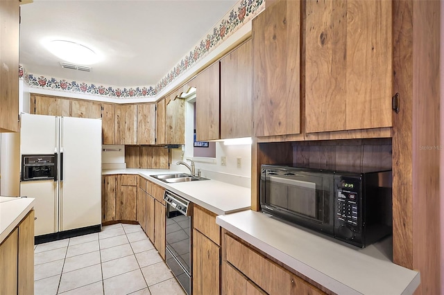 kitchen featuring sink, light tile patterned flooring, and black appliances