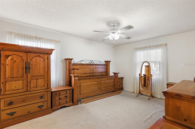 bedroom featuring light carpet, ceiling fan, and a textured ceiling