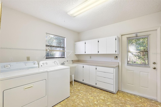 laundry room with sink, cabinets, separate washer and dryer, and a textured ceiling