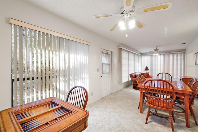 dining room with ceiling fan and light carpet