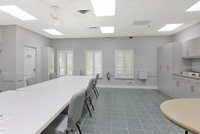 tiled dining room with a drop ceiling and ceiling fan