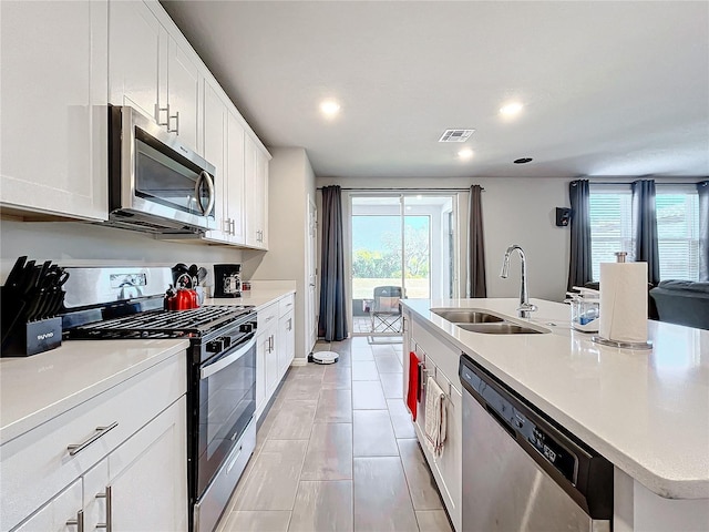 kitchen featuring a healthy amount of sunlight, sink, stainless steel appliances, and an island with sink