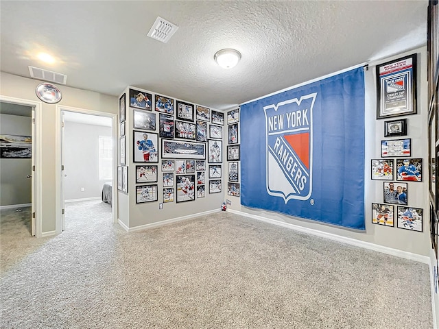 recreation room featuring carpet and a textured ceiling