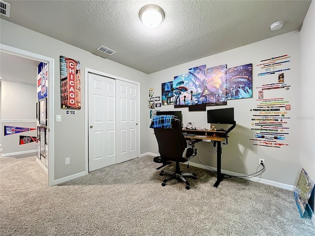 carpeted home office featuring a textured ceiling