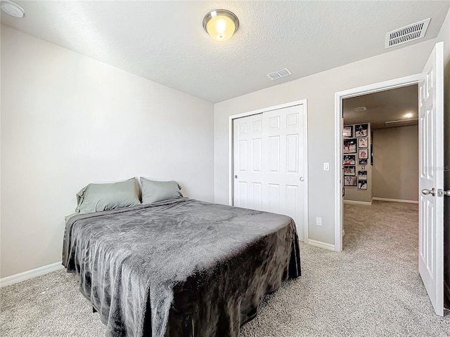 bedroom with light colored carpet, a textured ceiling, and a closet