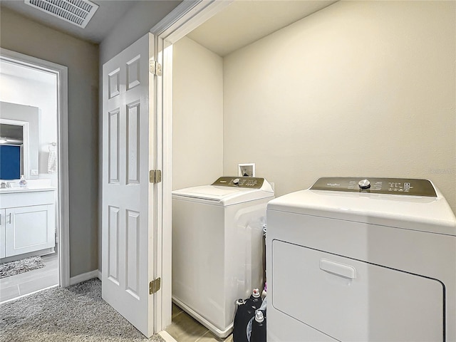 clothes washing area with washing machine and dryer, light carpet, and sink