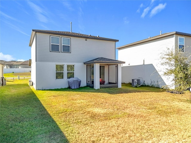 rear view of house featuring a sunroom, a yard, and cooling unit