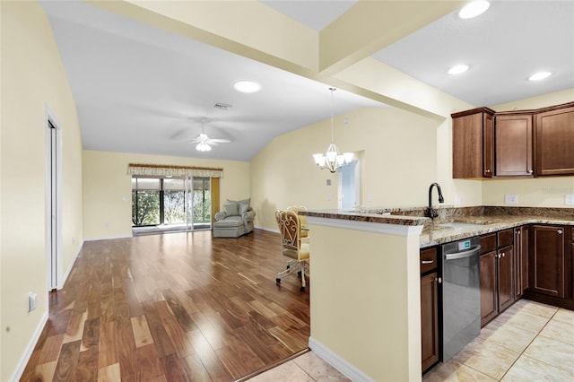 kitchen with light wood-type flooring, light stone counters, stainless steel dishwasher, ceiling fan with notable chandelier, and lofted ceiling