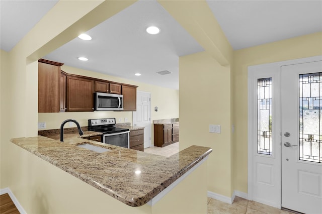 kitchen featuring kitchen peninsula, appliances with stainless steel finishes, light stone countertops, sink, and light tile patterned flooring