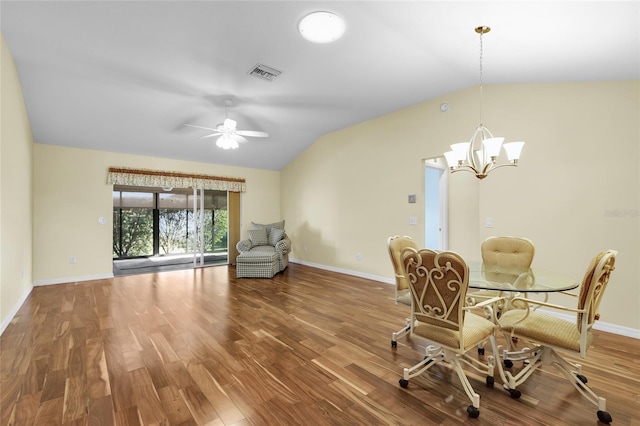 dining area featuring ceiling fan with notable chandelier, wood-type flooring, and vaulted ceiling