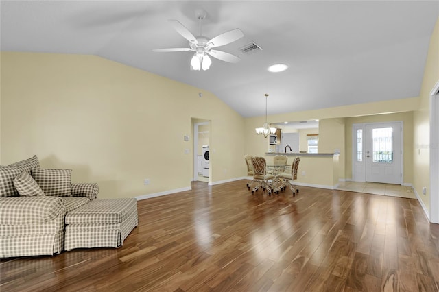 interior space with wood-type flooring, ceiling fan with notable chandelier, washer / clothes dryer, and vaulted ceiling