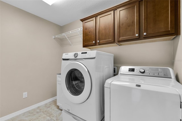 laundry area featuring cabinets, light tile patterned floors, washing machine and dryer, and a textured ceiling