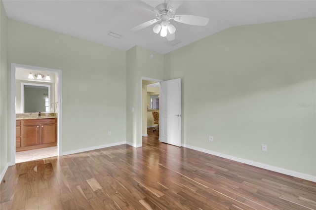 unfurnished bedroom with ceiling fan, sink, ensuite bathroom, lofted ceiling, and hardwood / wood-style flooring