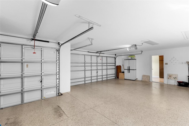 garage featuring white fridge and a garage door opener