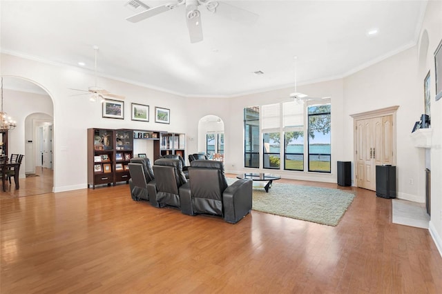 living room featuring ceiling fan with notable chandelier, light wood-type flooring, and ornamental molding