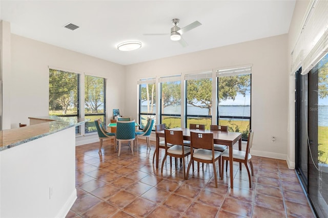 dining room featuring tile patterned floors, ceiling fan, and a water view