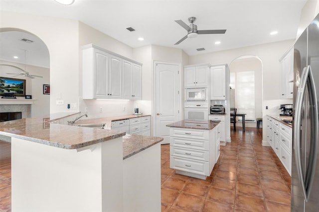 kitchen with white cabinets, white appliances, kitchen peninsula, and sink